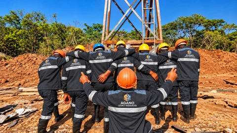 An AGANO team in charcoal branded workwear and hard hats beside mine headgear.