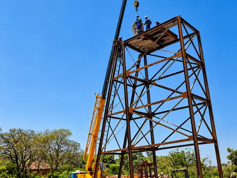 A mobile crane and workers beside a steel mine headgear structure.